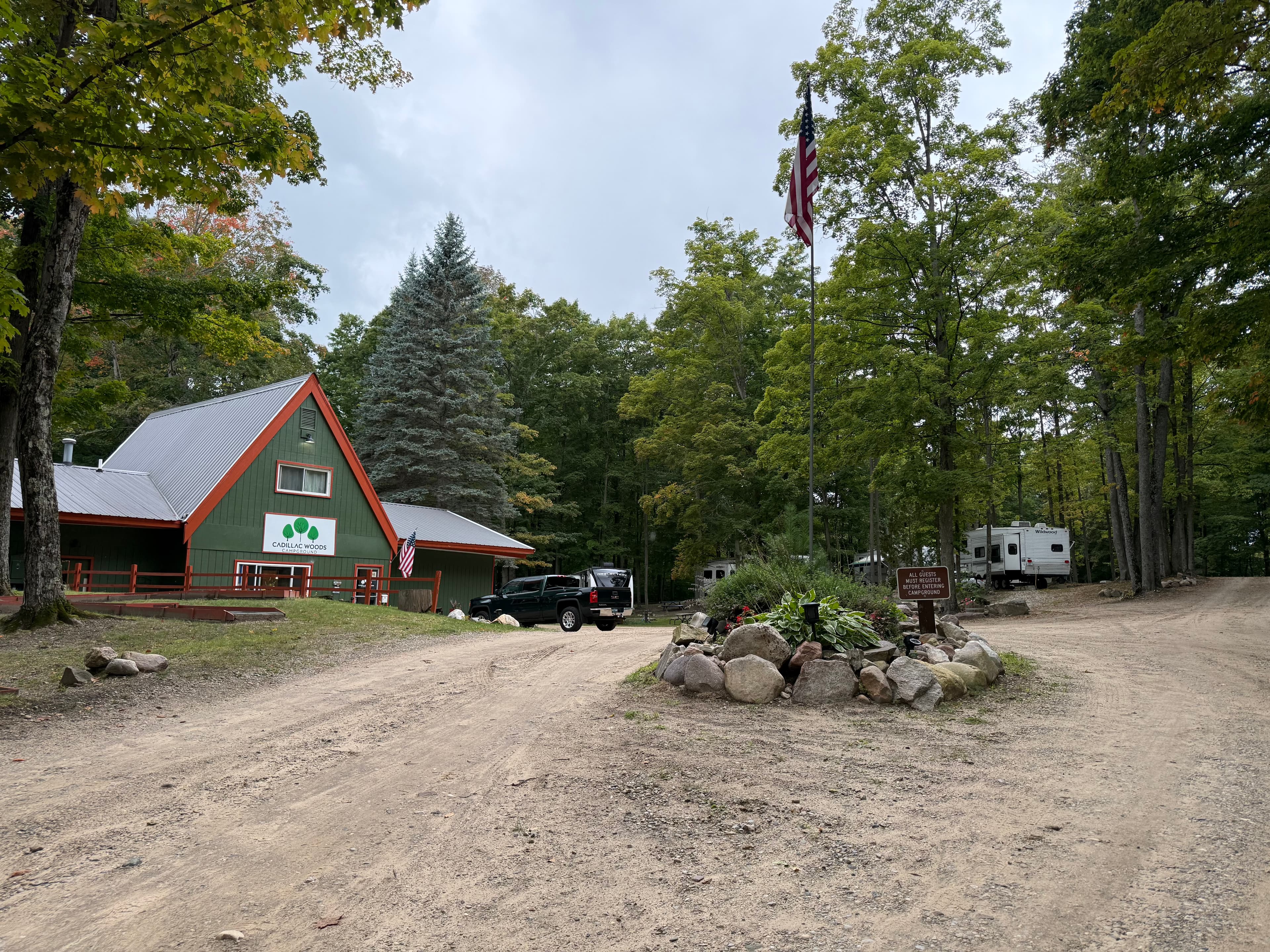 Cadillac Woods office with the American flag and wooded campsites nearby